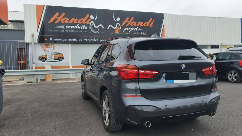 Cercle accélérateur manuel sous volant à tirer et levier de frein au volant sur une BMW X1 par Handi Conduite dans l'Hérault