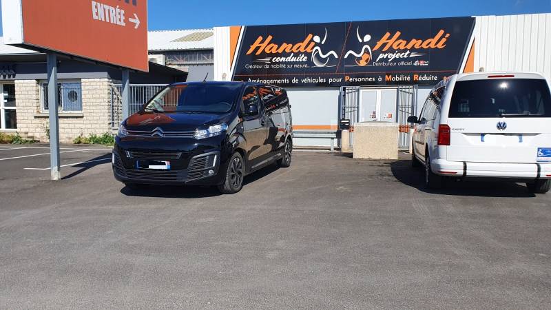 Adaptation d'un Citroën Jumpy pour le retour à l'autonomie d'une personne handicapée avec cercle accélérateur sous volant, levier de frein manuel à baisser et planche de transfert électrique par Handi Conduite dans l'Hérault